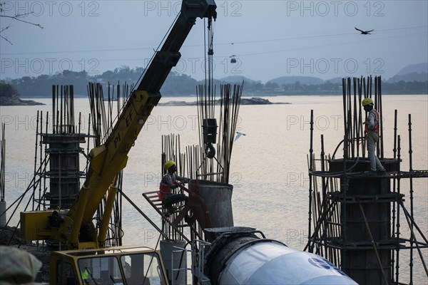 Construction workers busy build pillars of a bridge in the banks of Brahmaputra river on April 3