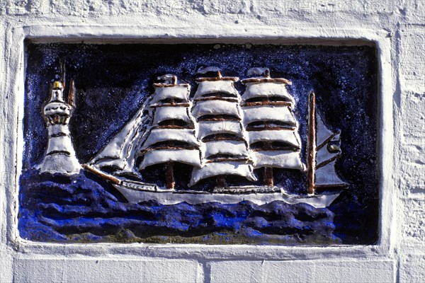 Ceramic relief of a sailing ship and a lighthouse