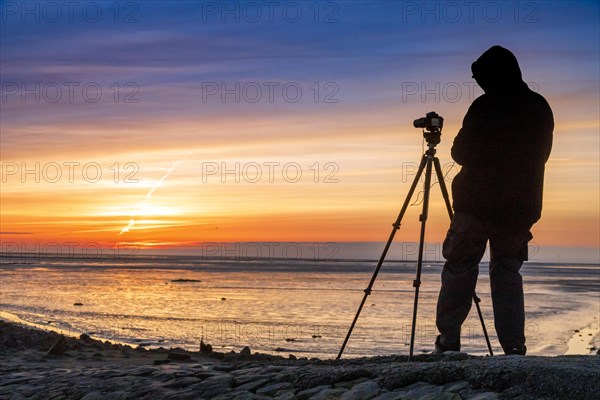 Tourist with camera during sunset on the Trischendamm