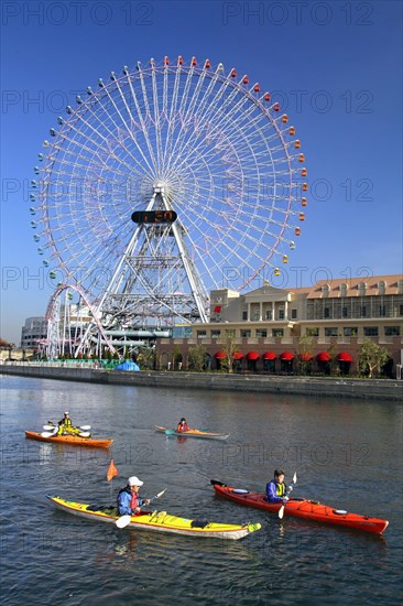 Group of kayaks on excursion and Ferris Wheel Cosmo Clock 21 of Yokohama Cosmo World in background Yokohama city Kanagawa Japan