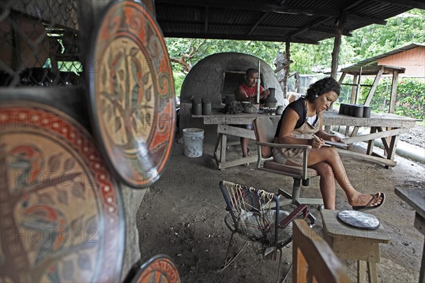 Costa Rican woman and man painting plates and vases according to the Chorotega Indian tradition