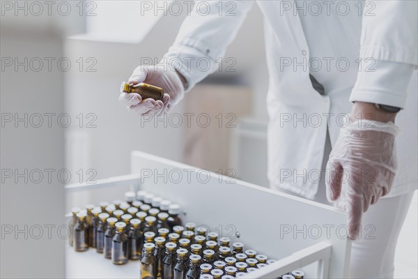 A prescription worker takes a dropper bottle from a drawer
