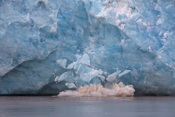 Huge ice chunk breaking from the edge of the Kongsbreen glacier calving into Kongsfjorden