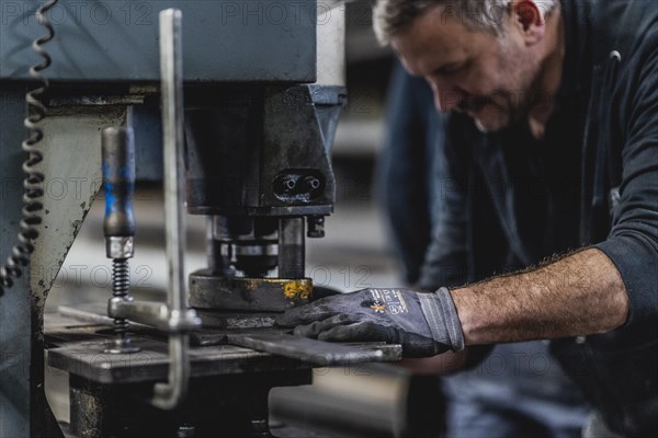 A metal worker clamps a piece of metal into a machine