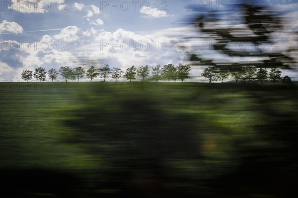 Landscape in central Germany. View from a moving train onto meadows and trees