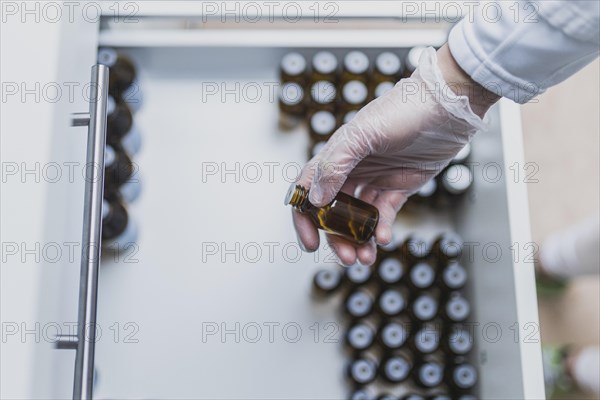A prescription worker takes a dropper bottle from a drawer