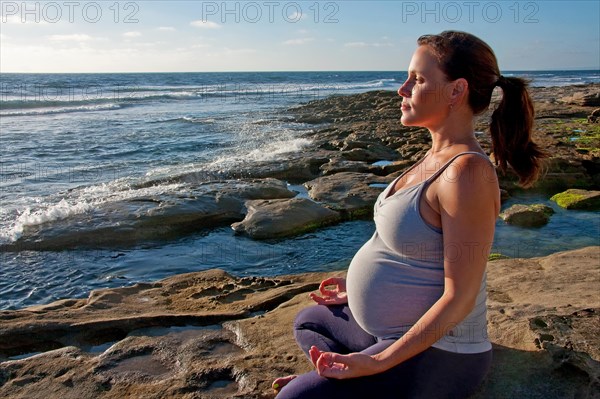 Beautiful pregnant woman doing yoga outdoors b&w