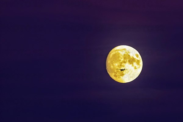 Small single-engine private plane in front of the full moon