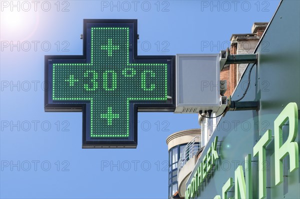 Thermometer in green pharmacy screen sign displays extremely hot temperature of 30 degrees Celsius during heatwave