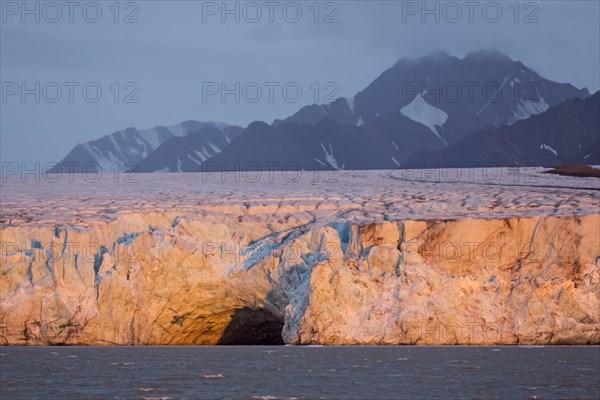 Entrance of giant ice cave at sunset in the Kongsbreen glacier calving into Kongsfjorden