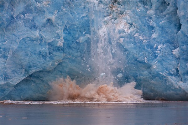 Huge ice chunk breaking from the edge of the Kongsbreen glacier calving into Kongsfjorden