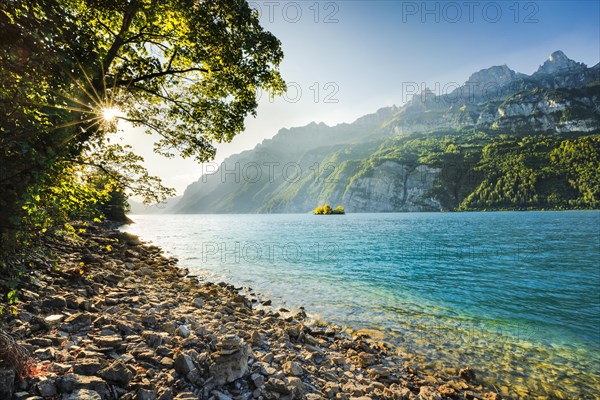 Last light over Lake Walen with the small chive island in the turquoise water and mountain range Leistchamm in the background