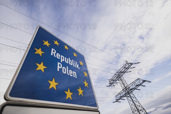 Border sign towards Poland in front of an electricity pylon