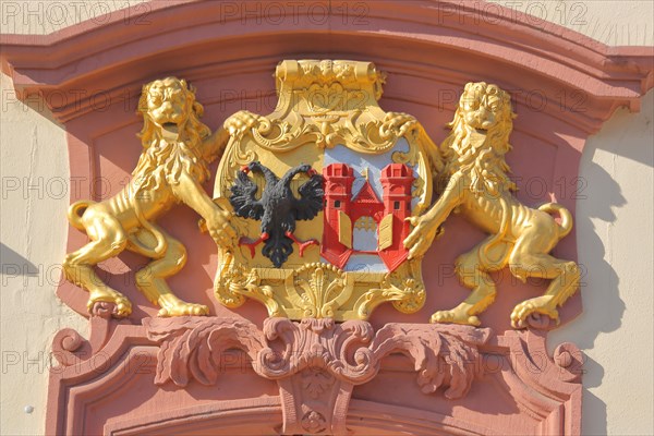 Golden town coat of arms with lion figure and double-headed eagle on the town hall