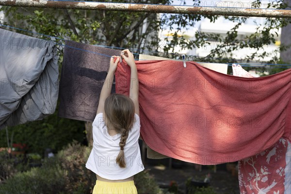 Child hanging laundry on a clothesline .