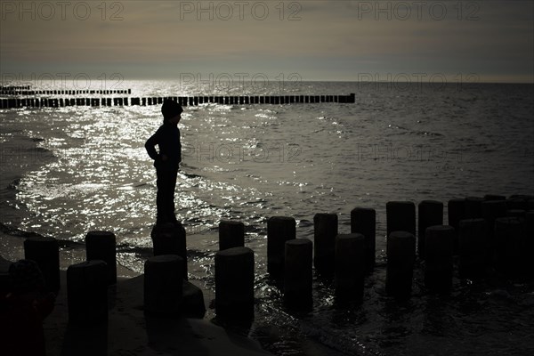 Symbolic photo on the theme of children's courage. A child balances on wooden stilts over the water. Arenshoop