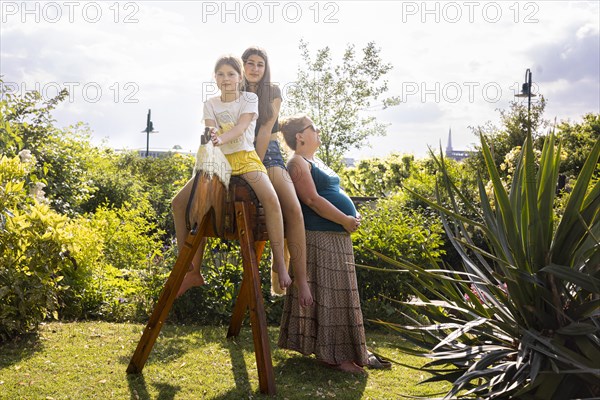 Woman with two girls sitting on a wooden horse