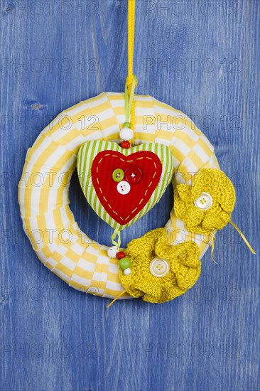 Decorative wreath on blue background and fabric heart