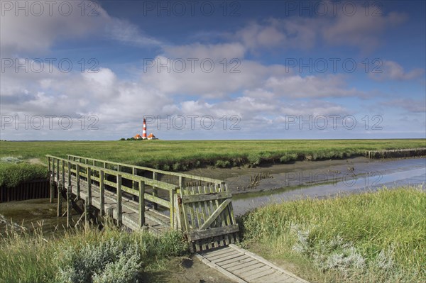 Wooden footbridge and lighthouse Westerheversand at Westerhever