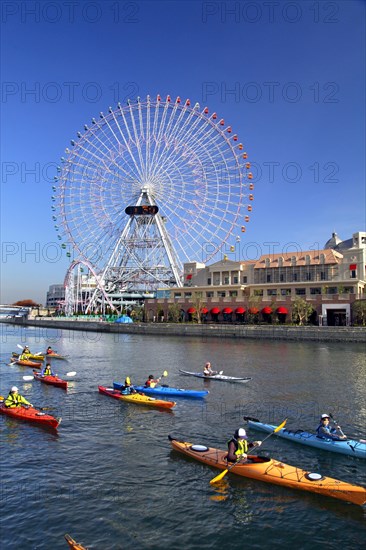 Group of kayaks on excursion and Ferris Wheel Cosmo Clock 21 of Yokohama Cosmo World in background Yokohama city Kanagawa Japan