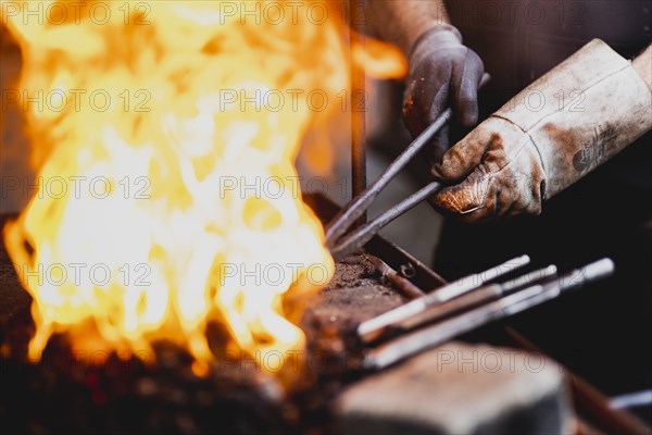 A metalworker works at the forge fire