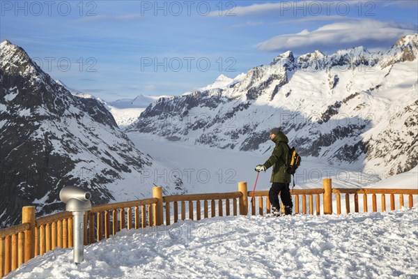 Tourist in the snow looking over the mountains in winter surrounding the Swiss Aletsch Glacier