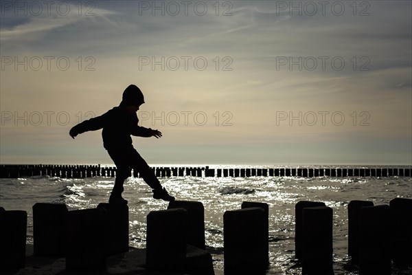 Symbolic photo on the theme of children's courage. A child balances on wooden stilts over the water. Arenshoop