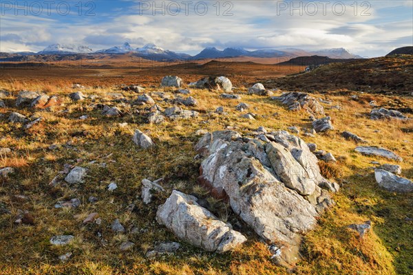 Striking boulders in the wintry Scottish Highlands with the snow-capped mountains of Suilven and Stack Polly in the background