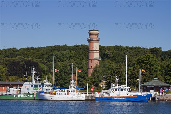 Coastguard patrol boats and the old lighthouse in the port of Travemuende at dusk