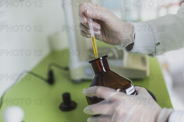 An employee in a pharmacy uses a disposable pipette for virgin olive oil in the prescription