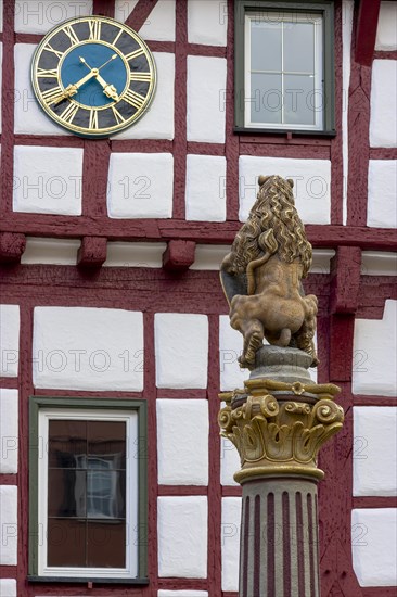 Detail of the sculpture at the market fountain and behind the half-timbered house and the large wall clock