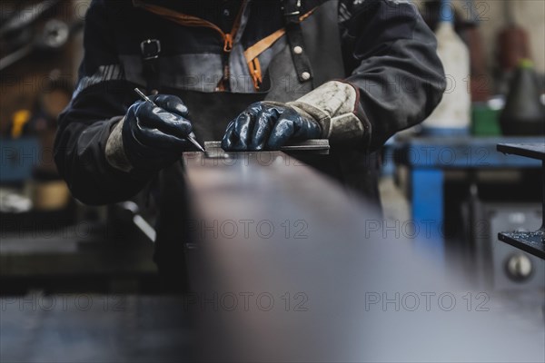 A metalworker marks with an angle on a steel beam