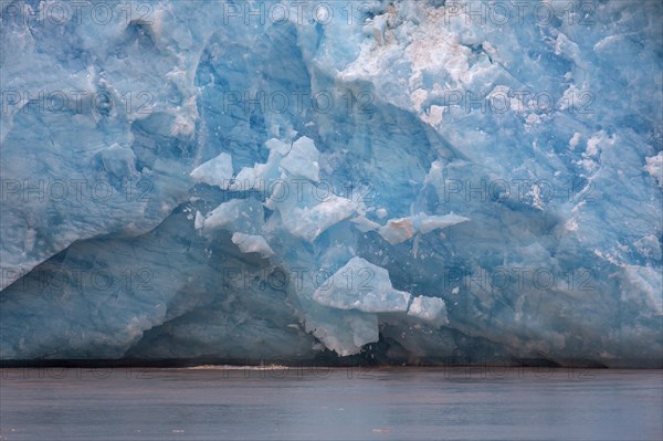 Huge ice chunk breaking from the edge of the Kongsbreen glacier calving into Kongsfjorden