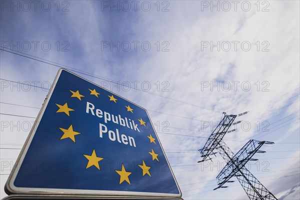 Border sign towards Poland in front of an electricity pylon