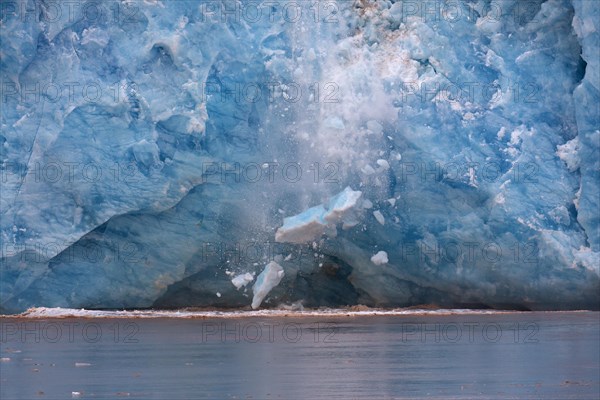 Huge ice chunk breaking from the edge of the Kongsbreen glacier calving into Kongsfjorden