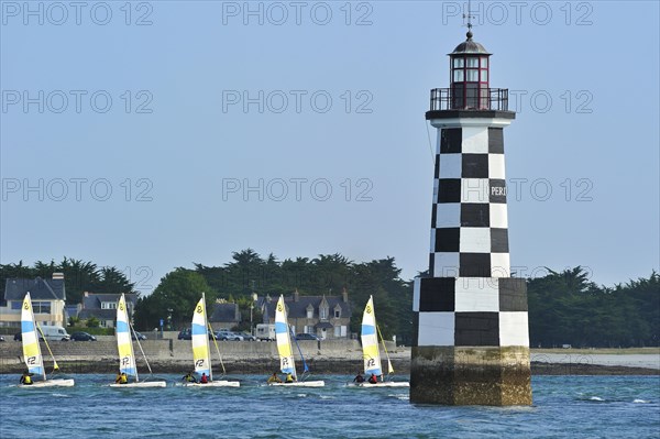 Dinghies from sailing school passing by the lighthouse Perdrix at Loctudy