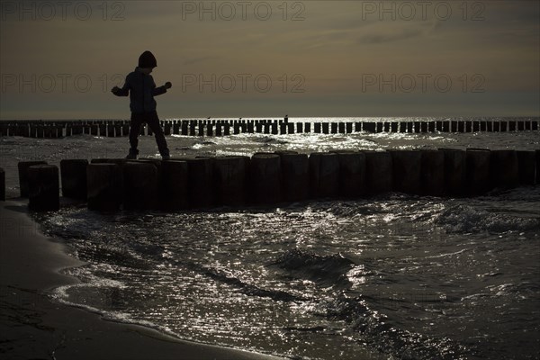 Symbolic photo on the subject of children's fear. A child balances on wooden stilts over the water. Arenshoop