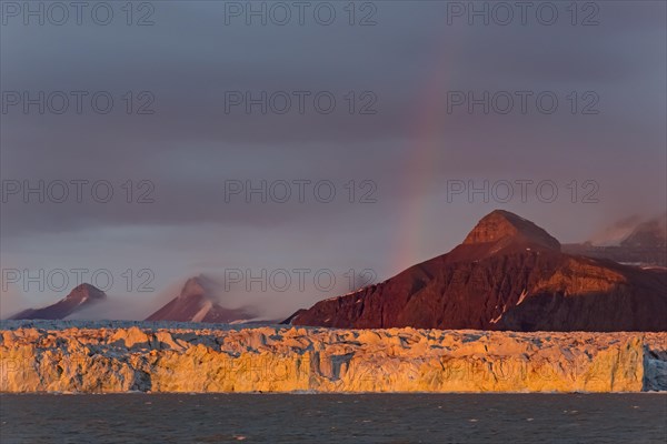 Rainbow over the Kongsbreen glacier in evening light at sunset