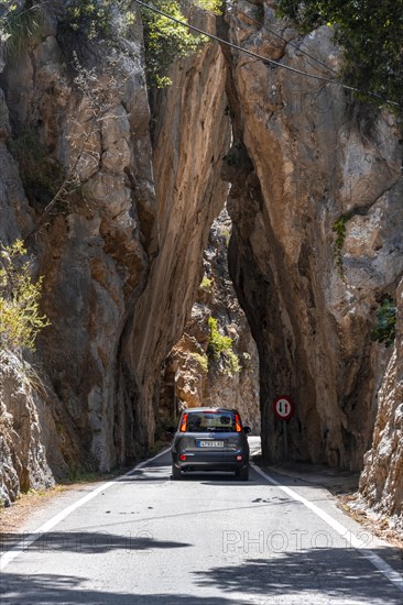 Car at a tunnel of rocks at the mountain pass to Sa Colobra