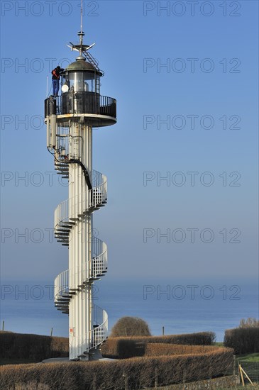 Worker wearing safety harness doing maintenance work on the Alprech lighthouse with spiralling exterior staircase near Le Portel