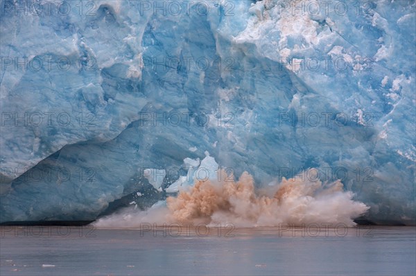 Huge ice chunk breaking from the edge of the Kongsbreen glacier calving into Kongsfjorden