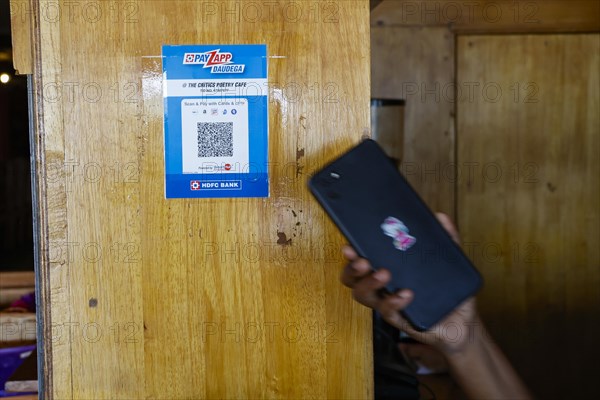 A hand holds a mobile phone to a QR code for cashless payment at the Critics Poetry Cafe coffee shop in Trichy