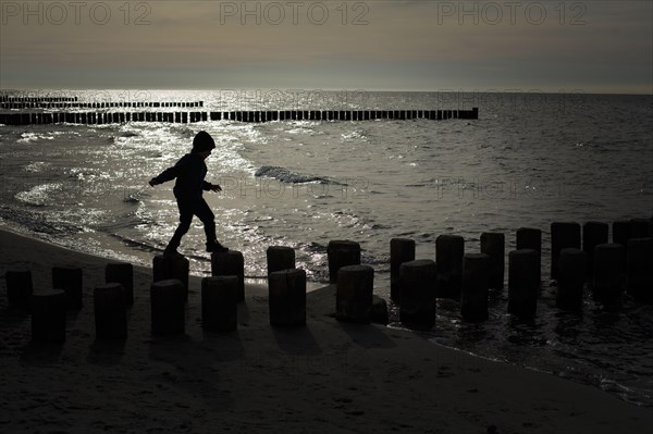 Symbolic photo on the theme of children's courage. A child balances on wooden stilts over the water. Arenshoop