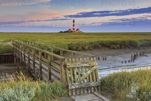 Wooden footbridge and lighthouse Westerheversand at Westerhever