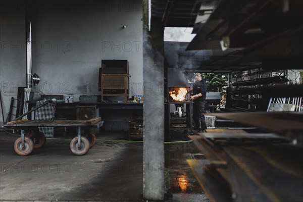 A metalworker works at the forge fire