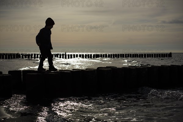 Symbolic photo on the subject of children's fear. A child balances on wooden stilts over the water. Arenshoop