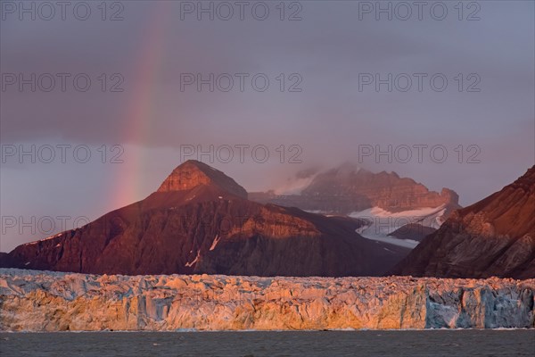 Rainbow over the Kongsbreen glacier in evening light at sunset