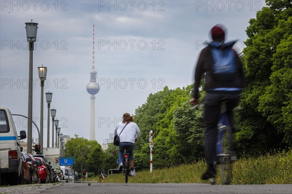 Cyclists ride along Karl Marx Allee on a cycle path towards Mitte. The television tower can be seen in the background. Berlin