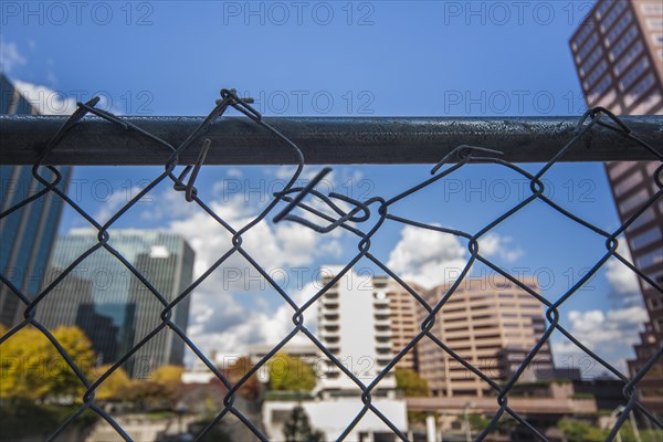 Broken chain-link fence in front of office buildings