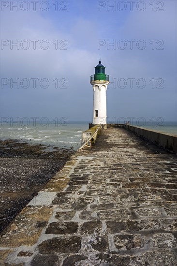 Lighthouse and lonely man looking at sea from pier in the harbour at Saint-Valery-en-Caux